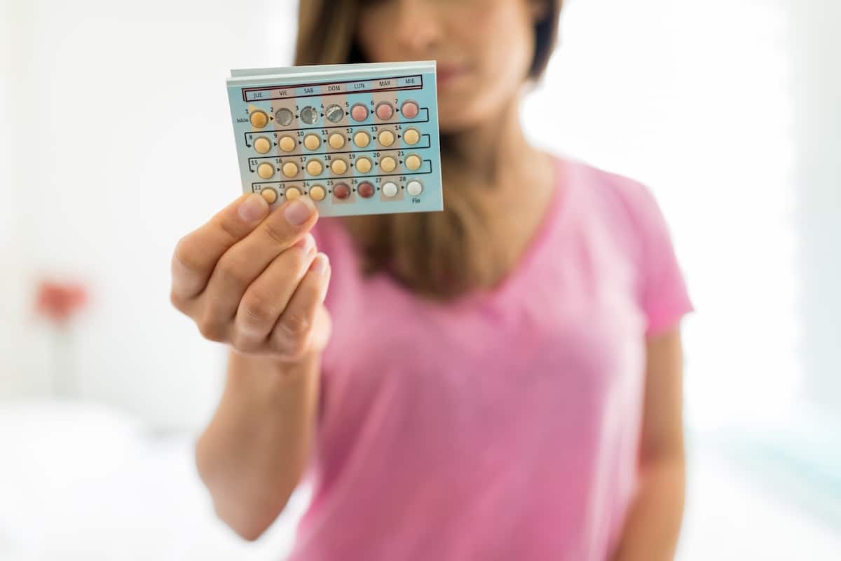 woman holding up a pack of birth control